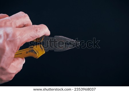 pliers, wire cutters, yellow handle in the hand of an asian man