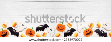 Halloween cookie bottom border. Top view on a white wood banner background with copy space. Ghosts, bats, jack o lanterns and candy corn.