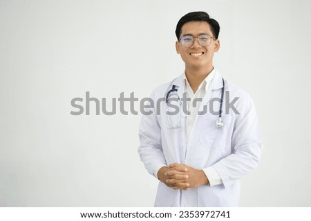 Portrait of happy and successful asian doctor working inside office clinic looking at camera and smiling wearing white coat with stethoscope. Royalty-Free Stock Photo #2353972741