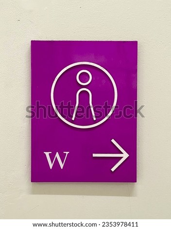 A pink female restroom sign in front of the restroom.