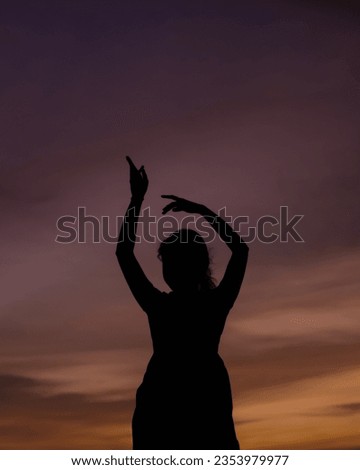 A silhouette of a girl dancing at sunset