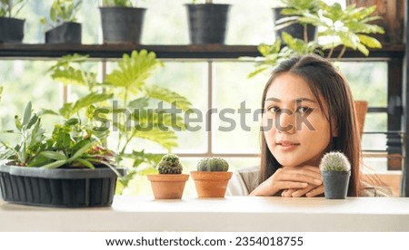 Portrait garden beautiful pretty young Asian woman wearing white blouse with long black hair and smile fresh happy relax bright smile look hand holding pot small tree leafgreen plant in room shop 