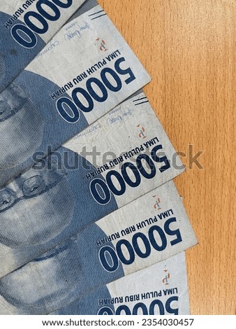 Indonesian rupiah money photo isolated on wooden desk background. Uang kertas rupiah Indonesia