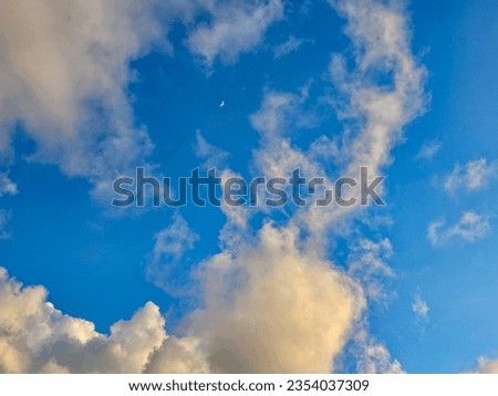 Perfect blue sky behind some blue tones clouds with moon in shot. Blue sky fluffy Clouds with half moon. Half moon on blue sky have white cloud. Stock Photos. Background, Desktop wallpaper