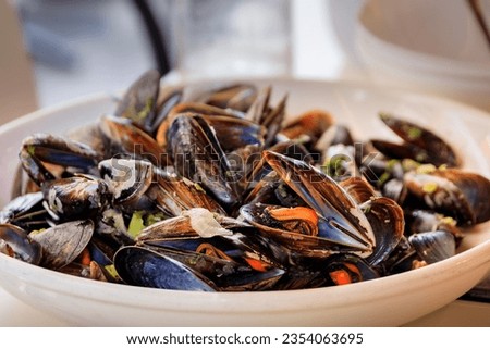 Freshly cooked mussels steamed in white wine sauce or moules marinieres on a plate at a restaurant in Nice Old Town, French Riviera, South of France Royalty-Free Stock Photo #2354063695