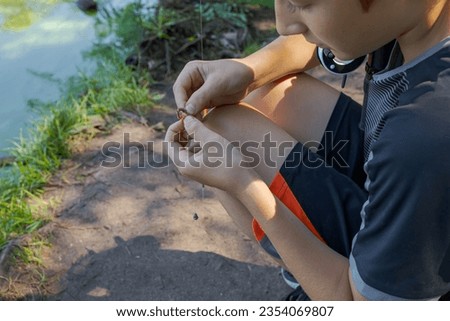 A teenager sets up a lure to catch fish. Sport fishing on the river in summer.
