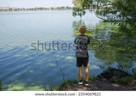 In nature by the river, a teenager catches fish. Sport fishing on the river in summer.