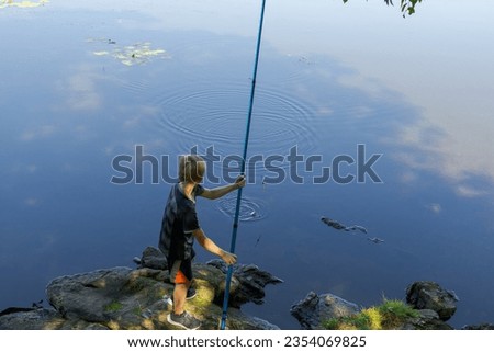 An overhead view of a teenager standing by a river fishing with a fishing rod. Sport fishing on the river in summer.