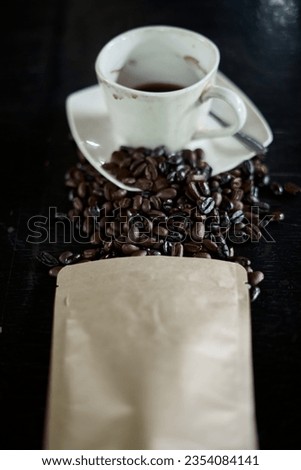 Glass of Coffee and Rosted arabica coffee beans with a black wood table background                               
