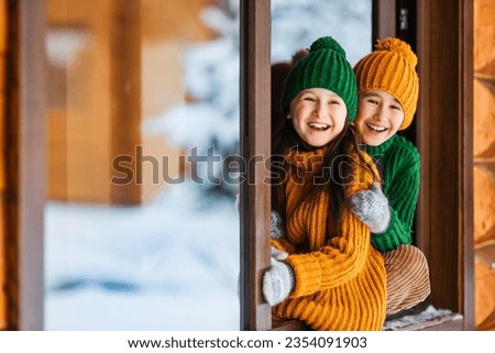 Hello winter holiday! Happy children play together outdoor in open window. Happy New Year and Merry Christmas family celebration! Royalty-Free Stock Photo #2354091903