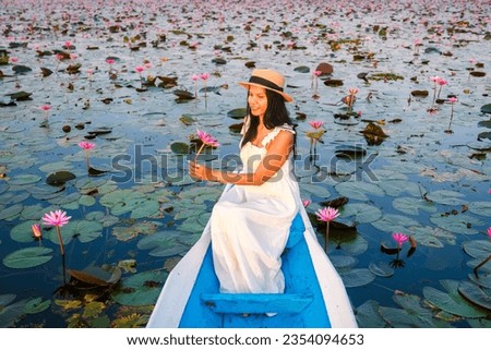 Asian women with a hat and dress in a boat at the Beautiful Red Lotus Sea Kumphawapi is full of pink flowers in Udon Thani in northern Thailand. Flora of Southeast Asia. 