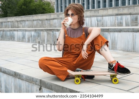Skateboarding. Female skater resting drinking coffee to go.