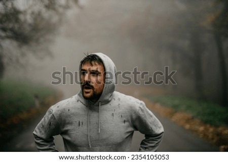 Close-up of a runner's determined expression as the pushes through the fog, determination clear in his eyes Royalty-Free Stock Photo #2354105053