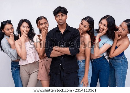 6 pretty asians look at and admire at a stoic and cool Indian guy. The campus crush and ladies man. 7 college students posing against a white backdrop. Royalty-Free Stock Photo #2354110361