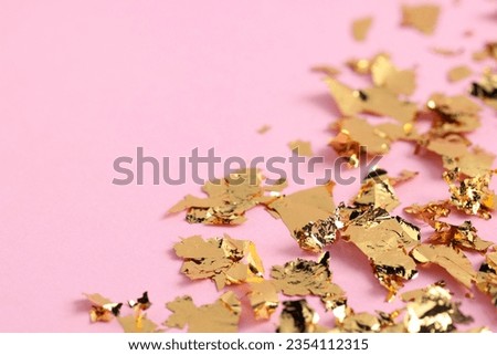 Many pieces of edible gold leaf on pink background, closeup. Space for text Royalty-Free Stock Photo #2354112315