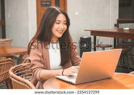 Smiling young Asian woman working remotely from cafe using her laptop, employee getting ready for online video-call interview Royalty-Free Stock Photo #2354137299