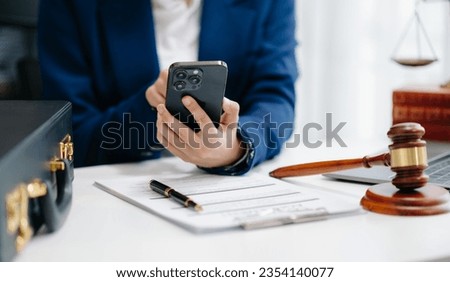 justice and law concept. Female judge in a courtroom the gavel, working with smart phone and laptop and digital tablet computer on white table in office