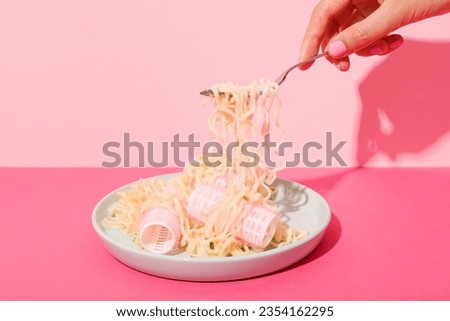 Noodles and curlers in plate, female hand on pink background