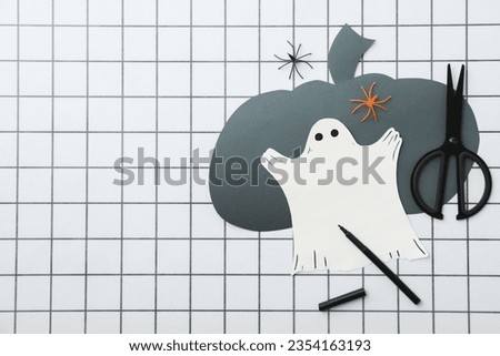 Scissors, paper pumpkin and ghost on light background, space for text