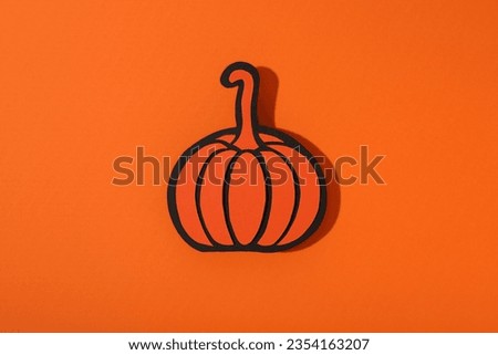 Paper pumpkin on orange background, top view