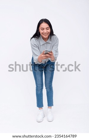 A young asian woman with mid-length bends down to take a photo. Possible college student. Isolated on a white backdrop.