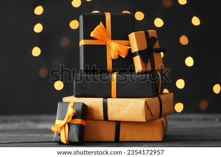 Gift boxes for Halloween celebration on black wooden table against blurred lights