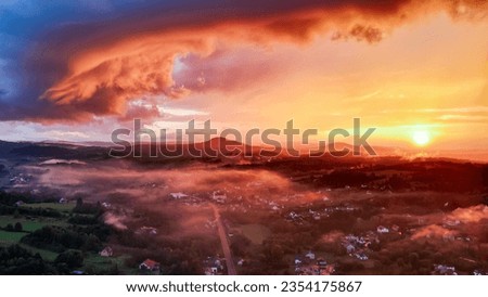 Aerial view of mountains at sunrise in autumn in Poland. Colorful landscape with mountain road, forest, houses on the hills, sunlight, sky in fall. Top view of roadway and village. sunset
