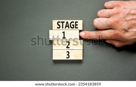 Time to stage 1 symbol. Concept word Stage 1 2 3 on wooden block. Businessman hand. Beautiful grey table grey background. Business planning and time to stage 1 concept. Copy space.