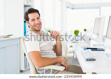 Relaxed smiling casual young business man with computer in a bright office