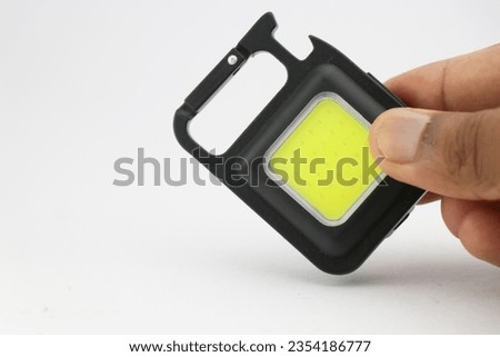 Small keychain pocket light with multiple features perfect during outdoor camping activities held in the hand with space for copy text Royalty-Free Stock Photo #2354186777