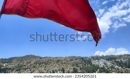 Red flag flying in the air blue sky over mountain 