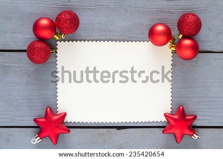 Blank paper for message with red christmas decoration on a wooden table.