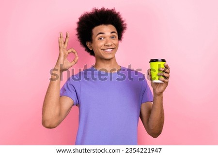 Photo of cheerful satisfied man wear stylish purple clothes recommend delicious coffee to go okey symbol isolated on pink color background