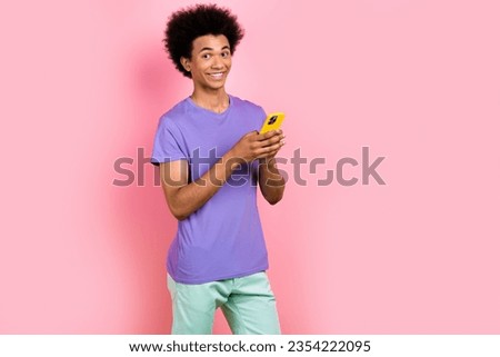 Photo of positive glad man wear stylish purple clothes hold modern gadget iphone empty space isolated on pink color background