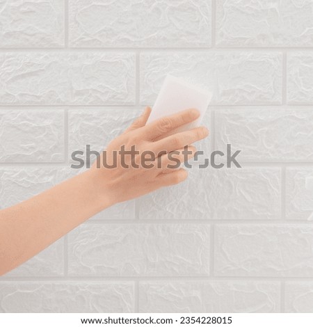White sponge in hand cleaning wall tiles. Cleaning concept and household product. Melamine. Royalty-Free Stock Photo #2354228015