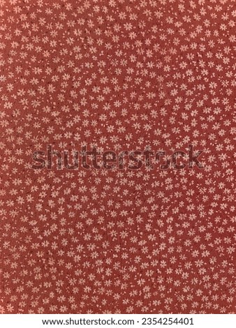 Fabric with seamless vintage ditsy floral pattern, closeup as a texture. Old fashioned, retro style cotton or linen textile with a print of scattered small yellowish flowers on rust red background Royalty-Free Stock Photo #2354254401