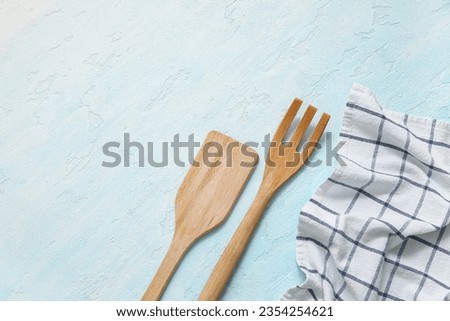 Wooden spatula, fork and napkin on blue background Royalty-Free Stock Photo #2354254621
