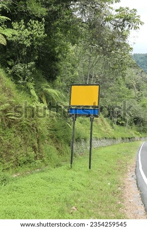 An unmarked billboard on a road with mountains in the background