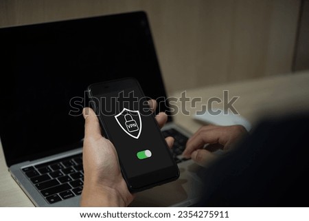 Male hand holding phone creates VPN for private network protection using Internet online. Royalty-Free Stock Photo #2354275911
