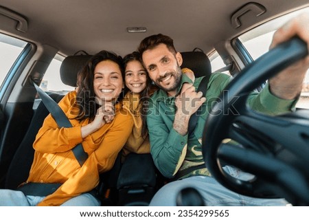 Automobile rent and purchase. Excited family embracing sitting in new car driving and enjoying road trip on vacation. Parents and daughter posing and smiling at camera in auto