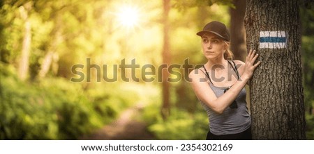Following a trail in the forest. Woman hiker at the trail sign. Empty copy space.