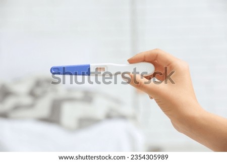 Female hand with positive pregnancy test on light background, closeup Royalty-Free Stock Photo #2354305989