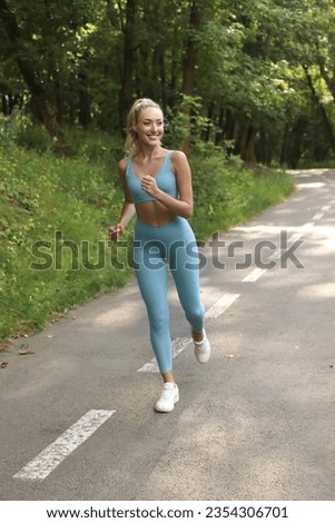 Full photo of Sporty smile woman is running in the park on a treadmill. Morning jogging. She is wearing in blue sportwear. She is happy. Royalty-Free Stock Photo #2354306701