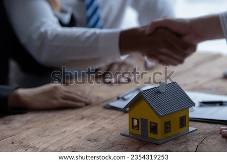 Close up focus on small house model standing on table with clients signing contract agreement with real estate agent, purchasing own dwelling apartment, professional service concept. Royalty-Free Stock Photo #2354319253
