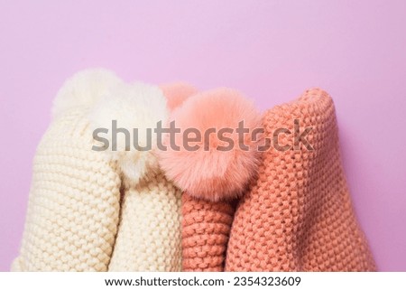 Knitted hats and scarves close-up on lilac background