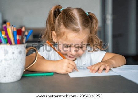 little girl draws with colored pencils in home. High quality photo. 