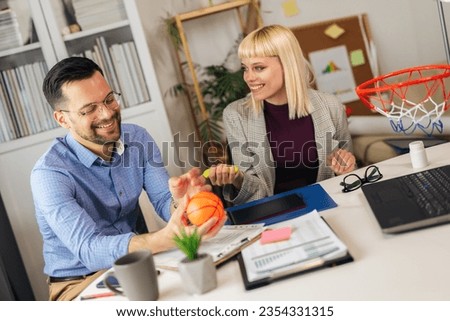 Portrait of young business people working together in home office having fun with basketball. Couple teamwork startup concept