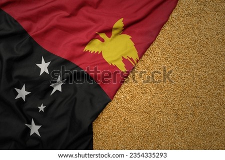 wheat grain on the waving colorful big national flag of Papua New Guinea .macro shot.