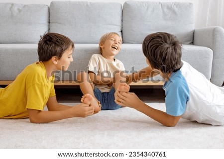 Happy positive children, tickling on the feet, having fun together, boy brothers at home having wonderful day of joy together Royalty-Free Stock Photo #2354340761