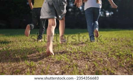 group of children run in the park on the grass. happy family kid dream concept. children with bare feet run on the grass in the park at sunset. bare feet group of kids run lifestyle in the park Royalty-Free Stock Photo #2354356683